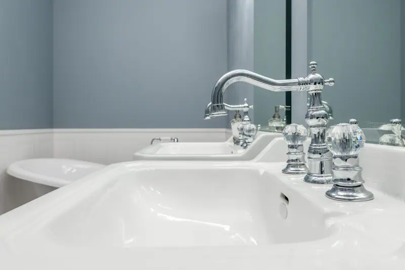 Twee witte wastafels met klassieke verchroomde kranen